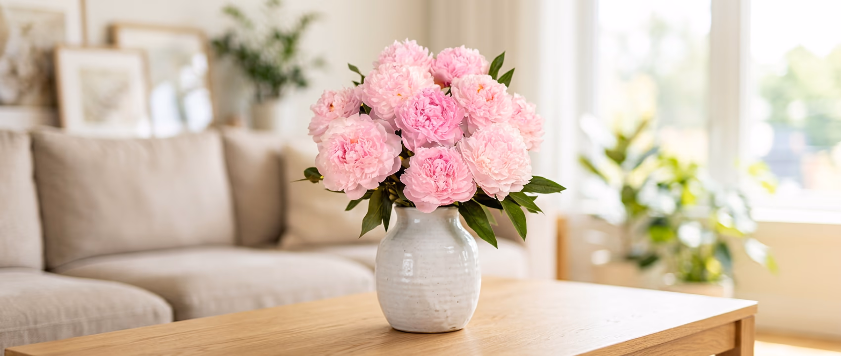 Pink peonies in a white vase placed on a table