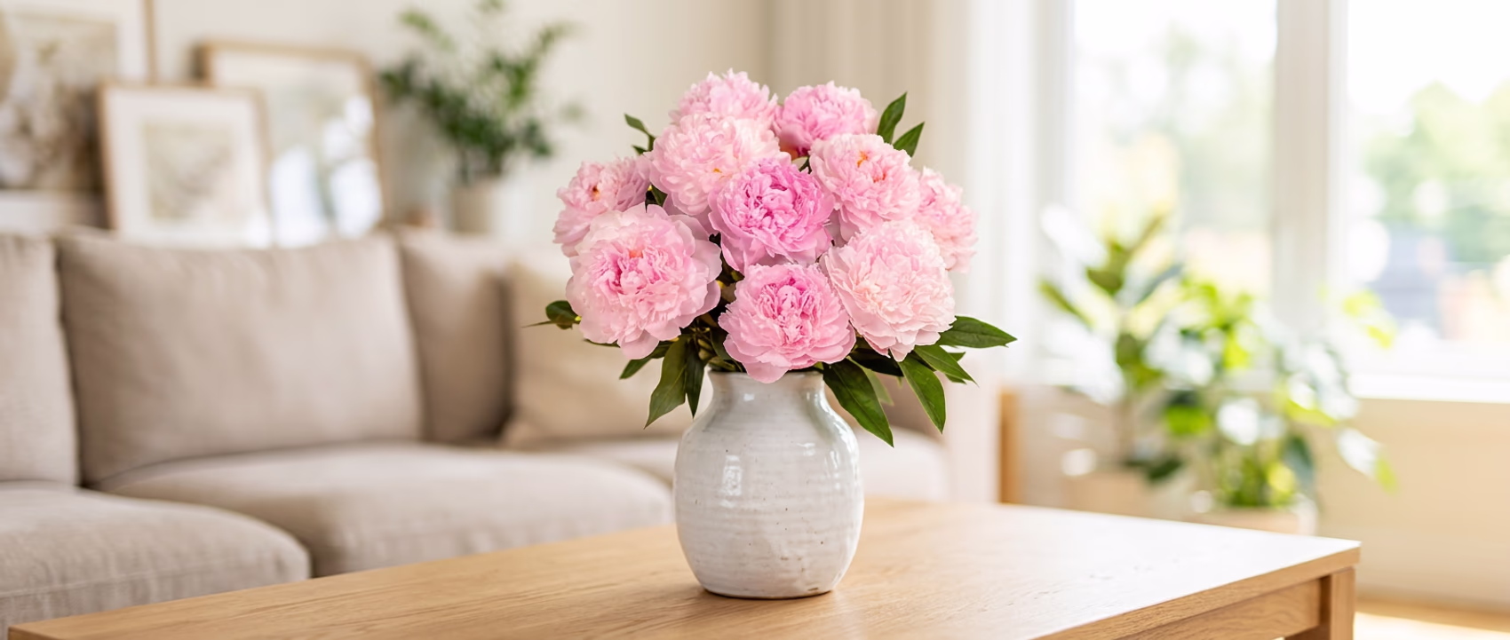 Pink peonies in a white vase placed on a table