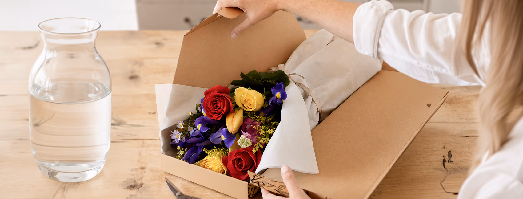 Letterbox flower parcel being opened to reveal a bunch of colourful flowers with 'Happiness Delivered' written in the open lid of the box.