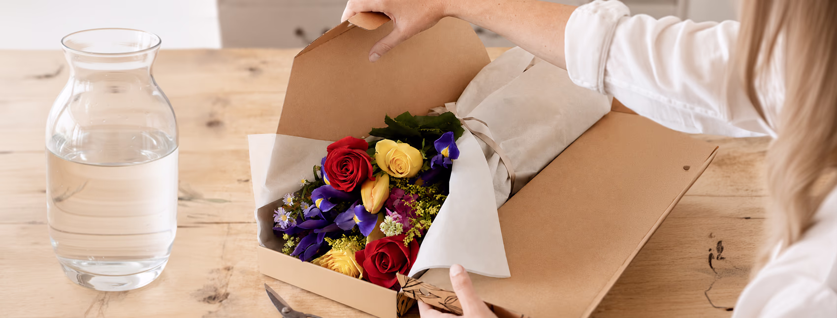 Letterbox flower parcel being opened to reveal a bunch of colourful flowers with 'Happiness Delivered' written in the open lid of the box.