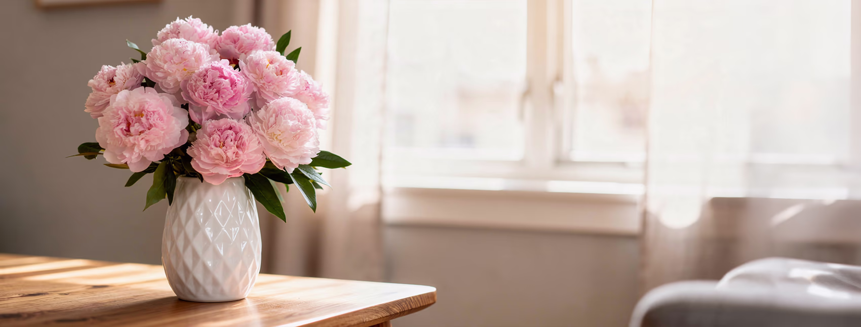 Pink peonies in a white vase placed on a table